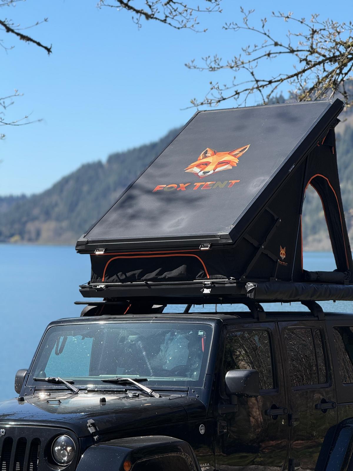 Jeep with FoxTent rooftop tent parked beside a mountain lake in British Columbia