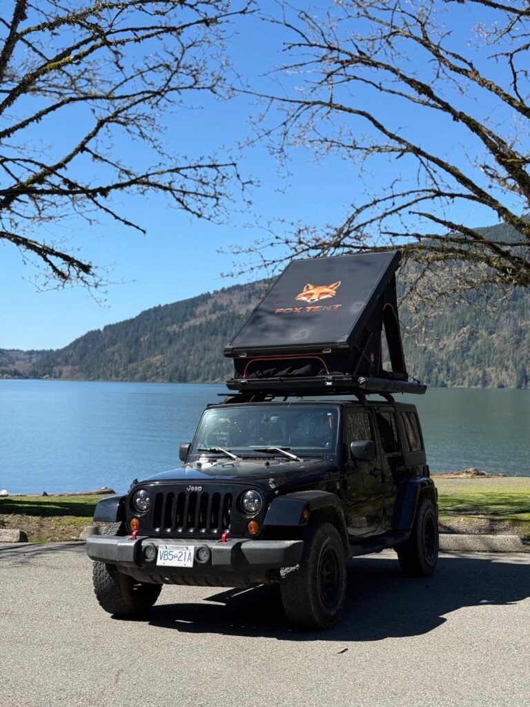 Black Jeep Wrangler with a FoxTent rooftop tent by a mountain lake in British Columbia